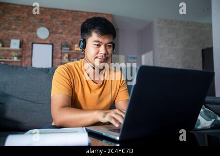 Gli uomini d'affari asiatici utilizzano computer notebook e indossano cuffie per riunioni online e lavorare da casa. Foto Stock