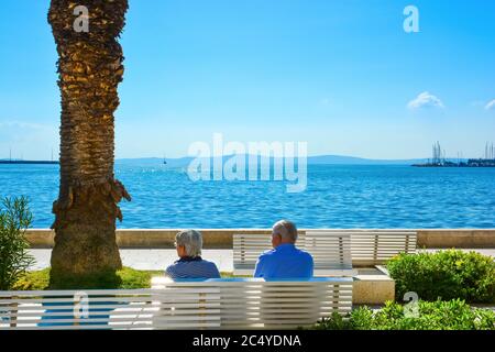 Una coppia matura si rilassa su una panchina sul lungomare di Riva, sulla costa dalmata di Spalato, Croazia Foto Stock