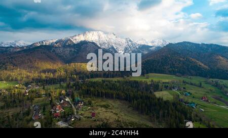Vista aerea delle montagne coperte di neve in estate o in primavera. Il massiccio montano di Giewont nei Monti Tatra e vista di Zakopane, Polonia, Europa Foto Stock
