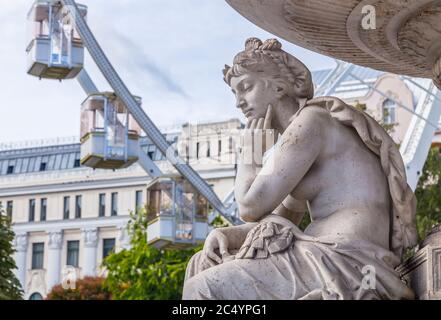 Frammento di scultura femminile della fontana danubius sullo sfondo della ruota di ferro dell'occhio di Sziget in Piazza Erzsebet a Budapest, Ungheria. Foto Stock