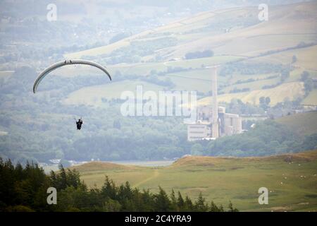 Parapendio al largo della collina di MAM Tor vicino Castleton nella cima alta del Derbyshire, Inghilterra incorniciato dalle opere di cemento Foto Stock