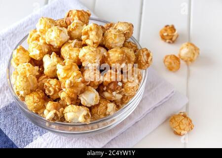 Popcorn dolce al caramello in una ciotola di vetro. Primo piano. Sfondo chiaro. Foto Stock