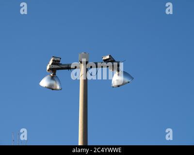 due luci a vapore al mercurio sulla sommità di un palo di cemento contro un cielo blu Foto Stock