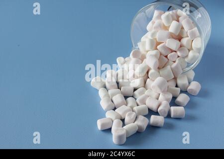 Marshmallows bianchi soffici in tazza isolati su sfondo blu. Mini marshmallows. Concetto di fondo del cibo invernale. Foto Stock