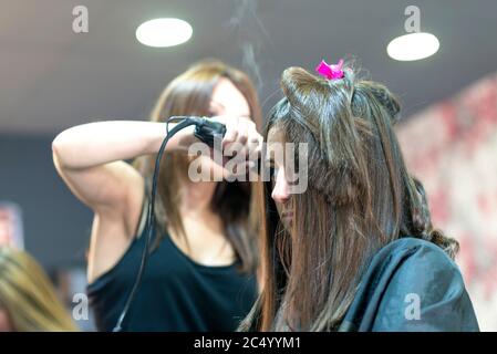 Parrucchiere raddrizzando i capelli lunghi marroni Foto Stock