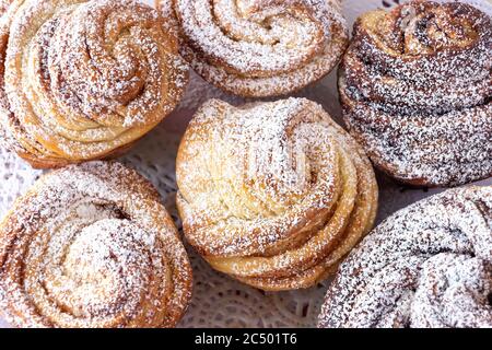 Torta cruffin moderna fatta in casa, panino di cannella arrotolato di lievito cosparso di zucchero in polvere. Spazio di copia. Sfondo. Primo piano. Vista dall'alto. Foto Stock