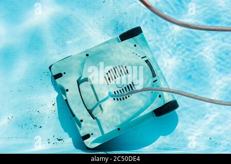 Vista dall'alto di un aspirapolvere robot da piscina subacqueo automatico che pulisce lo sporco sul pavimento. Foto Stock