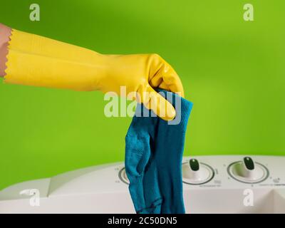 mani gugorate che lavano un calzino blu e sfondo verde Foto Stock