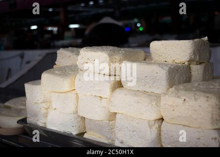 Blocchi di formaggio sono accatastati in un mercato locale, pronto per la vendita. Foto Stock