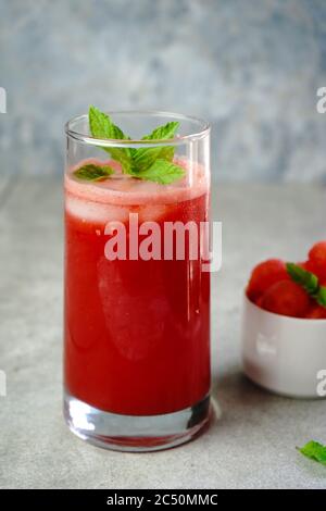 Succo di anguria rinfrescante in un bicchiere alto con guarnitura alla menta, fuoco selettivo Foto Stock