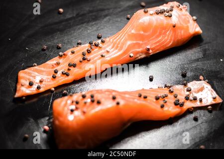 Filetto di pesce di salmone rosso di mare crudo su sfondo nero. Foto Stock