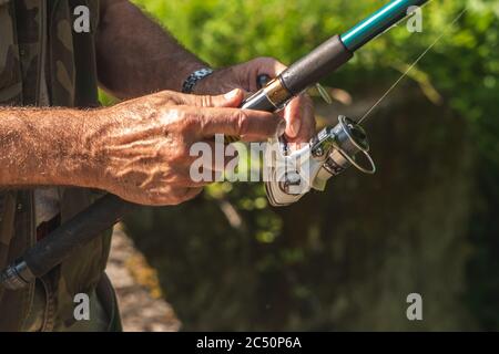 Pescatore che tiene fisher Rod, sfondo naturale Foto Stock