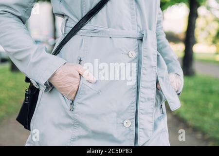 Ragazza in guanti medici mettere la sua mano nella tasca di un cappotto di primavera. Foto Stock