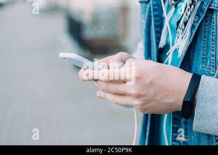 Un uomo che tiene in mano uno smartphone e digita un messaggio. Foto Stock