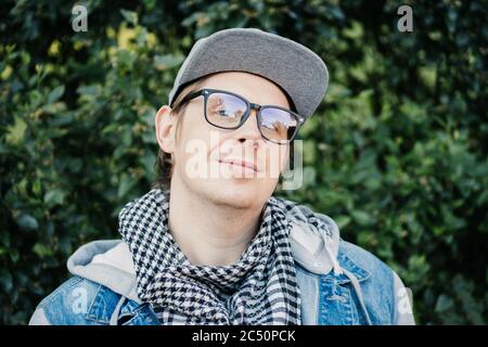 Ritratto di un giovane caucasico con bicchieri e un cappello nel parco Foto Stock