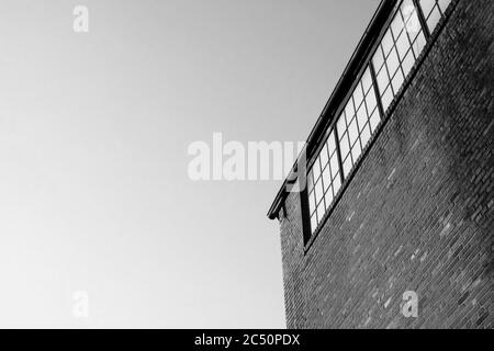 Foto in bianco e nero dell'angolo e del cielo di un edificio in una giornata nuvolosa. Foto Stock