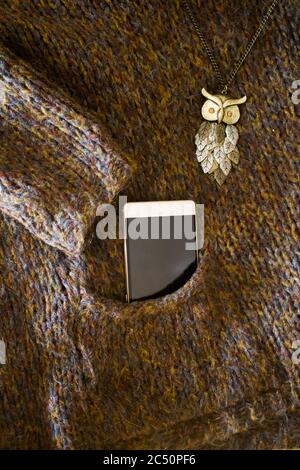 Maglia marrone di lana invernale in tasca con telefono Foto Stock