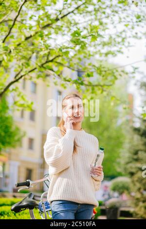 Bella donna che parla su smartphone in piazza verde. Foto Stock