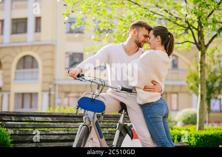 Giovane felice uomo in bicicletta e donna in piedi nelle vicinanze Foto Stock