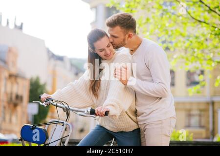 Donna in bicicletta e un uomo baciante che si trova nelle vicinanze Foto Stock