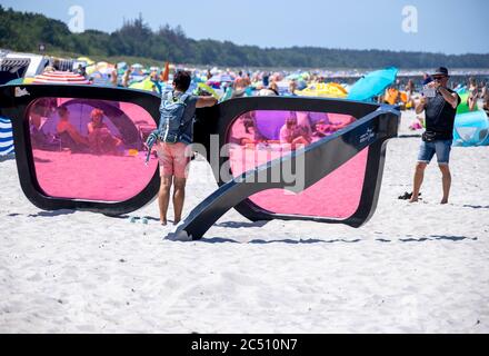 Zingst, Germania. 24 Giugno 2020. I grandi vetri rosa con il titolo 'Sea Pink II' di Marc Moser, mostra del festival fotografico 'Horizonte' 2016, sulla spiaggia del Mar Baltico. Con il sole e temperature intorno ai 25 gradi, molti turisti usano il tempo estivo per una giornata in spiaggia. Gli alberghi, le pensioni e i campeggi nelle regioni turistiche del Meclemburgo-Vorpommern sono attualmente molto ben utilizzati. Credit: Jens Büttner/dpa-Zentralbild/ZB/dpa/Alamy Live News Foto Stock