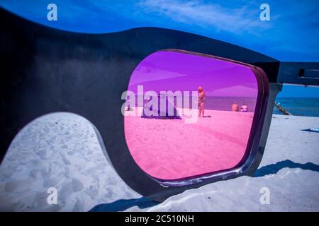 Zingst, Germania. 24 Giugno 2020. I grandi vetri rosa con il titolo 'Sea Pink II' di Marc Moser, mostra del festival fotografico 'Horizonte' 2016, sulla spiaggia del Mar Baltico. Con il sole e temperature intorno ai 25 gradi, molti turisti usano il tempo estivo per una giornata in spiaggia. Gli alberghi, le pensioni e i campeggi nelle regioni turistiche del Meclemburgo-Vorpommern sono attualmente molto ben utilizzati. Credit: Jens Büttner/dpa-Zentralbild/ZB/dpa/Alamy Live News Foto Stock