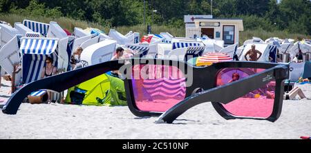 Zingst, Germania. 24 Giugno 2020. I grandi vetri rosa con il titolo 'Sea Pink II' di Marc Moser, mostra del festival fotografico 'Horizonte' 2016, sulla spiaggia del Mar Baltico. Con il sole e temperature intorno ai 25 gradi, molti turisti usano il tempo estivo per una giornata in spiaggia. Gli alberghi, le pensioni e i campeggi nelle regioni turistiche del Meclemburgo-Vorpommern sono attualmente molto ben utilizzati. Credit: Jens Büttner/dpa-Zentralbild/ZB/dpa/Alamy Live News Foto Stock