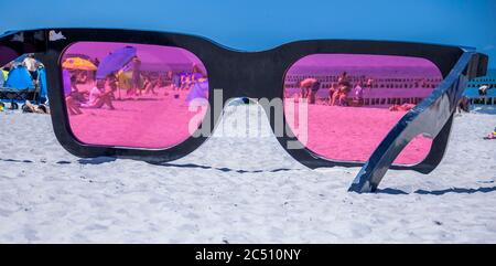 Zingst, Germania. 24 Giugno 2020. I grandi vetri rosa con il titolo 'Sea Pink II' di Marc Moser, mostra del festival fotografico 'Horizonte' 2016, sulla spiaggia del Mar Baltico. Con il sole e temperature intorno ai 25 gradi, molti turisti usano il tempo estivo per una giornata in spiaggia. Gli alberghi, le pensioni e i campeggi nelle regioni turistiche del Meclemburgo-Vorpommern sono attualmente molto ben utilizzati. Credit: Jens Büttner/dpa-Zentralbild/ZB/dpa/Alamy Live News Foto Stock