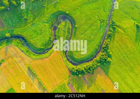 Vista aerea dall'alto della valle naturale di un fiume tortuoso tra campi verdi e boschi Foto Stock