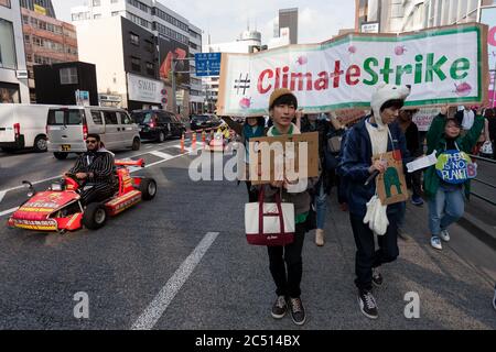 Shibuya, Giappone. 15 marzo 2019. I turisti in un tour in go-cart passano davanti ai giovani attivisti giapponesi che prendono parte allo Strike Globale per Future.These go cart tours commerciano l'idea di gioco Super Mario Carts e i personaggi sono una popolare attrazione turistica a Tokyo. Anche se ci sono problemi di sicurezza e copyright che potrebbero costringere presto l'azienda a smettere di eseguire i tour. Credit: Damon Coulter/SOPA Images/ZUMA Wire/Alamy Live News Foto Stock