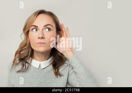 Donna attenta ad ascoltare notizie e pettegocini su sfondo bianco Foto Stock