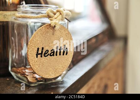 Vaso in vetro vintage retro con fascetta di corda canapa etichetta medica e poche monete all'interno su legno contro concetto di risparmio di denaro per la manutenzione sanitaria. Foto Stock