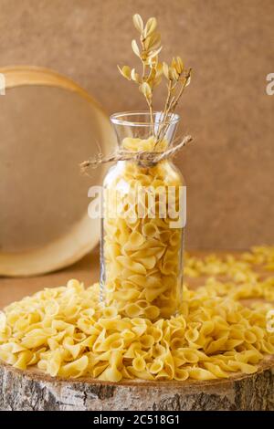 Pasta in un vaso, molta pasta è sparsa intorno, un vaso si trova su un supporto di legno Foto Stock