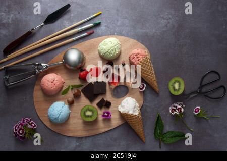I gelati estivi assortiti si raccolano su una tavolozza di pittori con sapori e ingredienti diversi Foto Stock