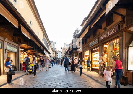 I turisti camminano sul famoso Ponte Vecchio, un ponte medievale ad arco in pietra con negozi costruiti insieme al Ponte Vecchio sul fiume Arno, a Firenze Foto Stock