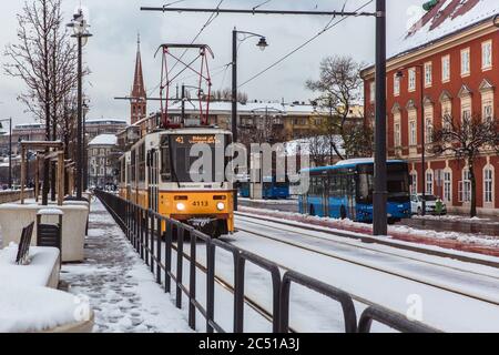 BUDAPEST, UNGHERIA - 02 DICEMBRE 2019: Tram giallo e tram a Budapest in inverno con neve vicino al argine sul lato Buda a Budapest. Foto Stock