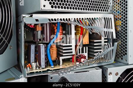 Componenti elettronici all'interno della scatola dell'unità di alimentazione del computer rotta. Primo piano di induttori, condensatori, trasformatori o dissipatori di calore in alluminio. Rifiuti elettronici. Eco. Foto Stock