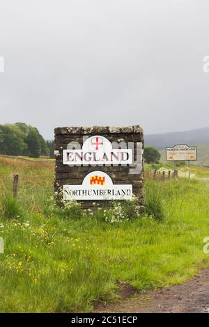 Pilastro di pietra e segni che segnano il confine tra Inghilterra e Scozia vicino su una strada non classificata a Deadwater, Kielder, Northumberland in una giornata noiosa e nebbiosa. Foto Stock