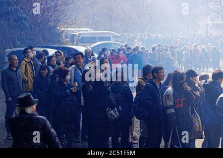 Il fumo si infila su una lunga fila di persone che aspettano il loro turno per attraversare lo spazio per i pompieri durante l'annuale festival dei pompieri vicino al Monte Takao Foto Stock