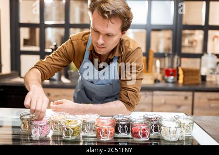 Confettiere che prova diversi additivi alimentari sotto forma di guarnizione per gelato al banco di un negozio Foto Stock