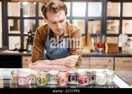 Confettiere che prova diversi additivi alimentari sotto forma di guarnizione per gelato al banco di un negozio Foto Stock