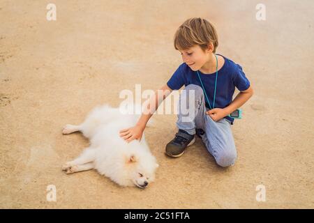 Piccolo ragazzo carino che stropica un cane furry Foto Stock