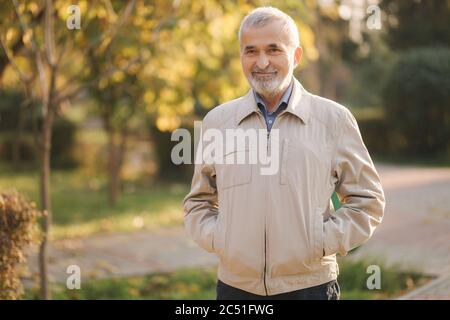 Bello bearder uomo anziano messo sui bicchieri. Capelli grigi vecchio uomo nel parco Foto Stock