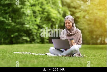 Bella ragazza araba che usa il computer portatile al parco pubblico Foto Stock