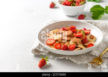 Colazione estiva alla moda con mini pancake e fragola su spazio copia bianco. Primo piano. Foto Stock