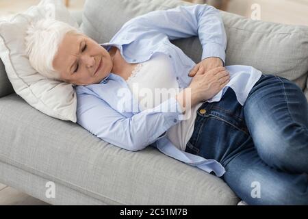 Pancreatite acuta. Triste donna anziana che tiene l'addome, soffre di mal di stomaco Foto Stock