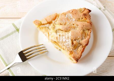 Un pezzo grande di torta di mele dolce e acide e forchetta su un piatto bianco su un tavolo di legno bianco. Ricetta semplice per una cottura dolce fatta in casa. Pasticceria per la colazione. Foto Stock