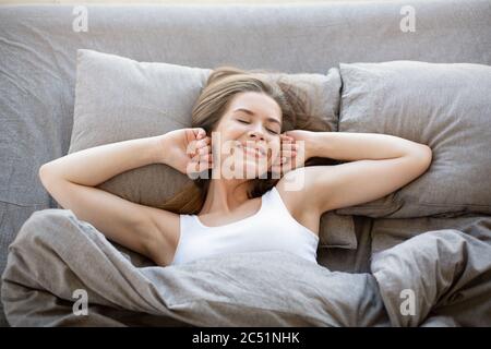 Bella ragazza giovane sdraiata su un letto comodo, essendo pigro la Domenica mattina, vista dall'alto Foto Stock