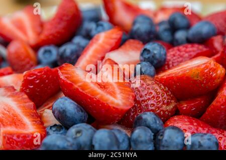 Una fotografia ravvicinata di una ciotola di fragole e mirtilli Foto Stock