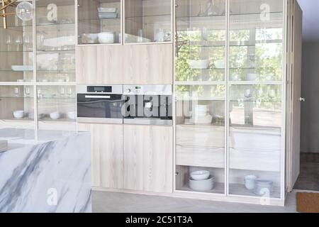 Cucina armadio bianco con utensili da cucina e piano cottura. Interni della cucina leggeri. Foto Stock